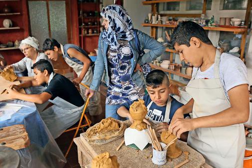 Flüchtlingskinder formen Puppenköpfe aus Ton